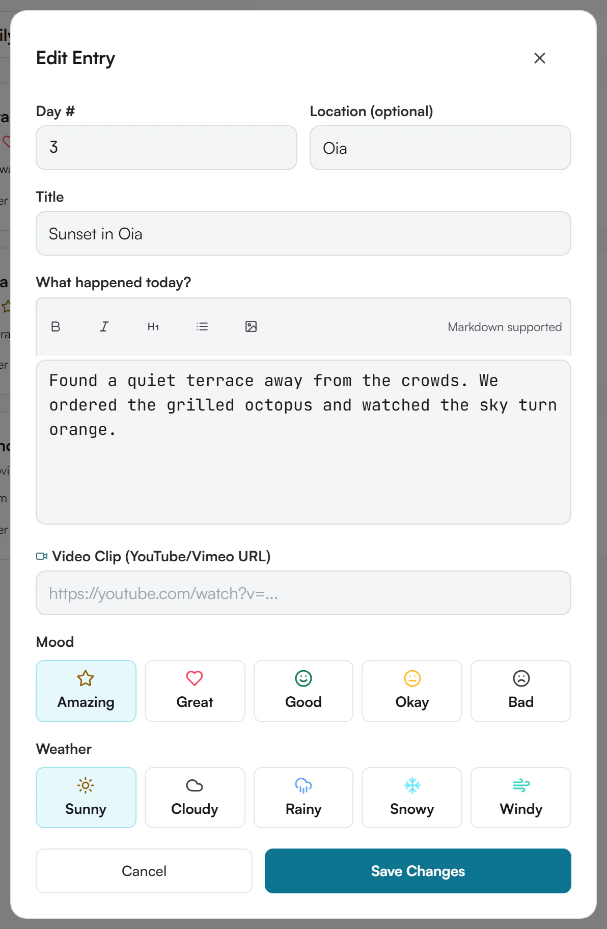 Edit Entry window with Day 3, Location Oia, the title Sunset in Oia, the text of the entry, an empty video field, the mood Amazing and the weather Sunny selected, and Cancel and Save Changes buttons